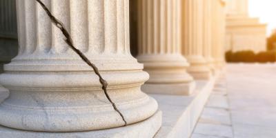 Cracked broken justice stone pillar in vintage courthouse.